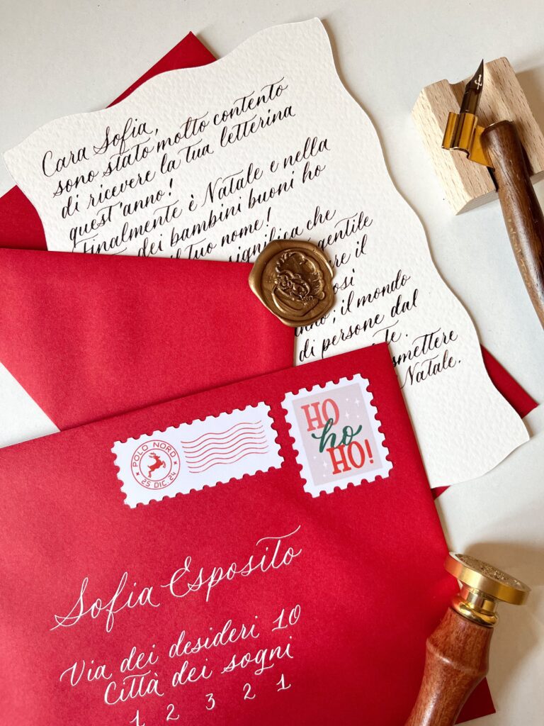 Foto di una lettera di risposta da Babbo Natale scritta a mano in calligrafia, con busta rossa e sigillo in ceralacca